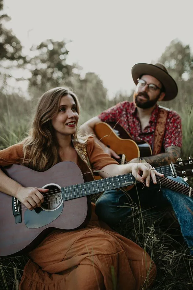 The duo Admiral Radio with acoustic guitars in a field of tall grass