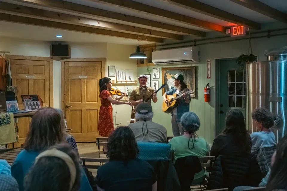A trio playing to a seated audience in a small room