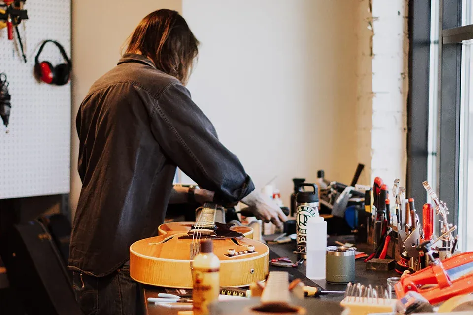 A luthier working on a guitar at the bench