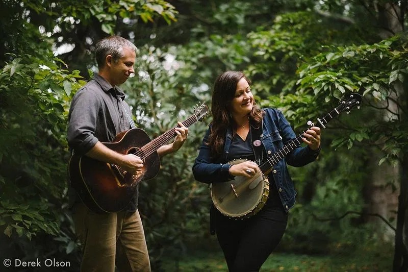 Nikki Talley and her bandmate playing guitar and banjo in the woods