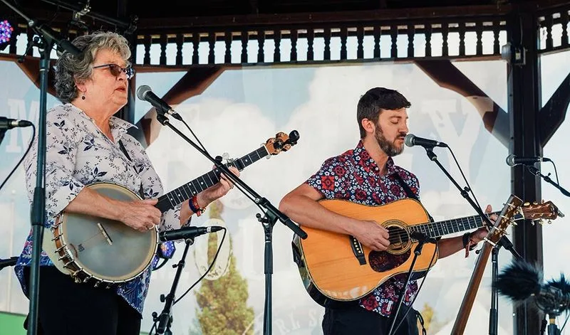 A banjo and guitar duo performing on a festival stage